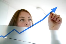 business woman drawing a graph on a glass window in an office - focus is on graph